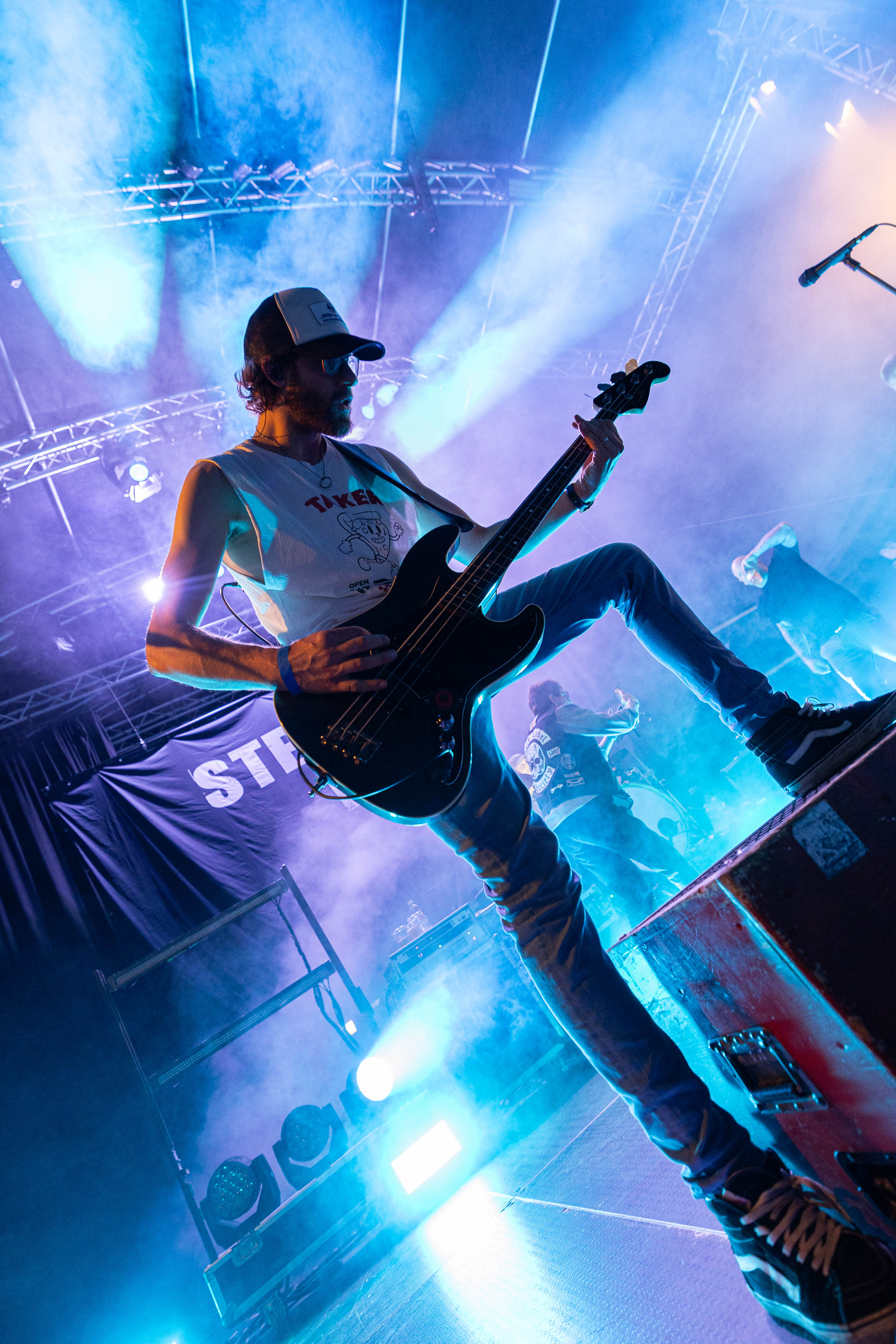 Bassist in blauem Bühnenlicht aus tiefer Perspektive