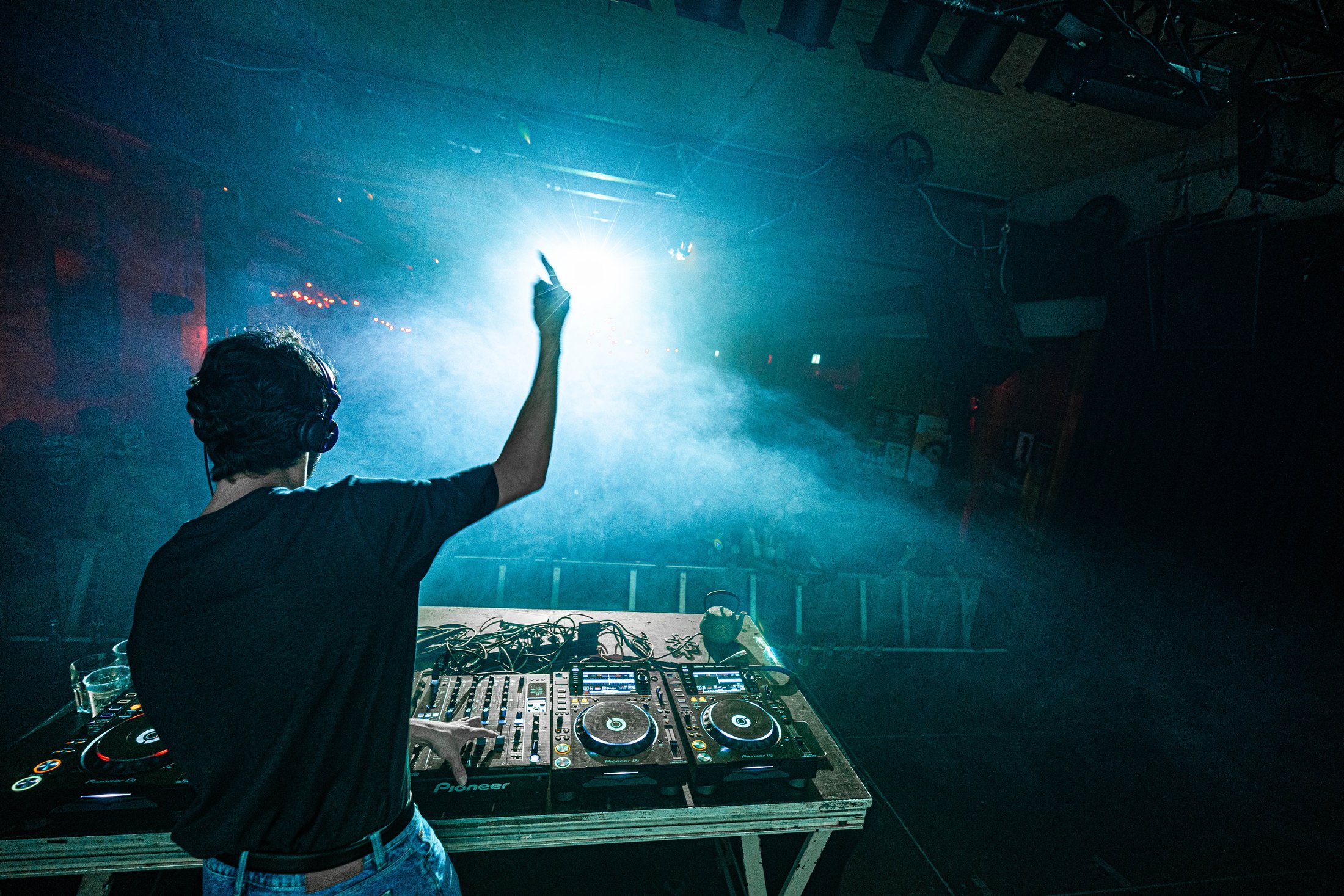 DJ vor einem dicht gefüllten Club im blauen Bühnenlicht
