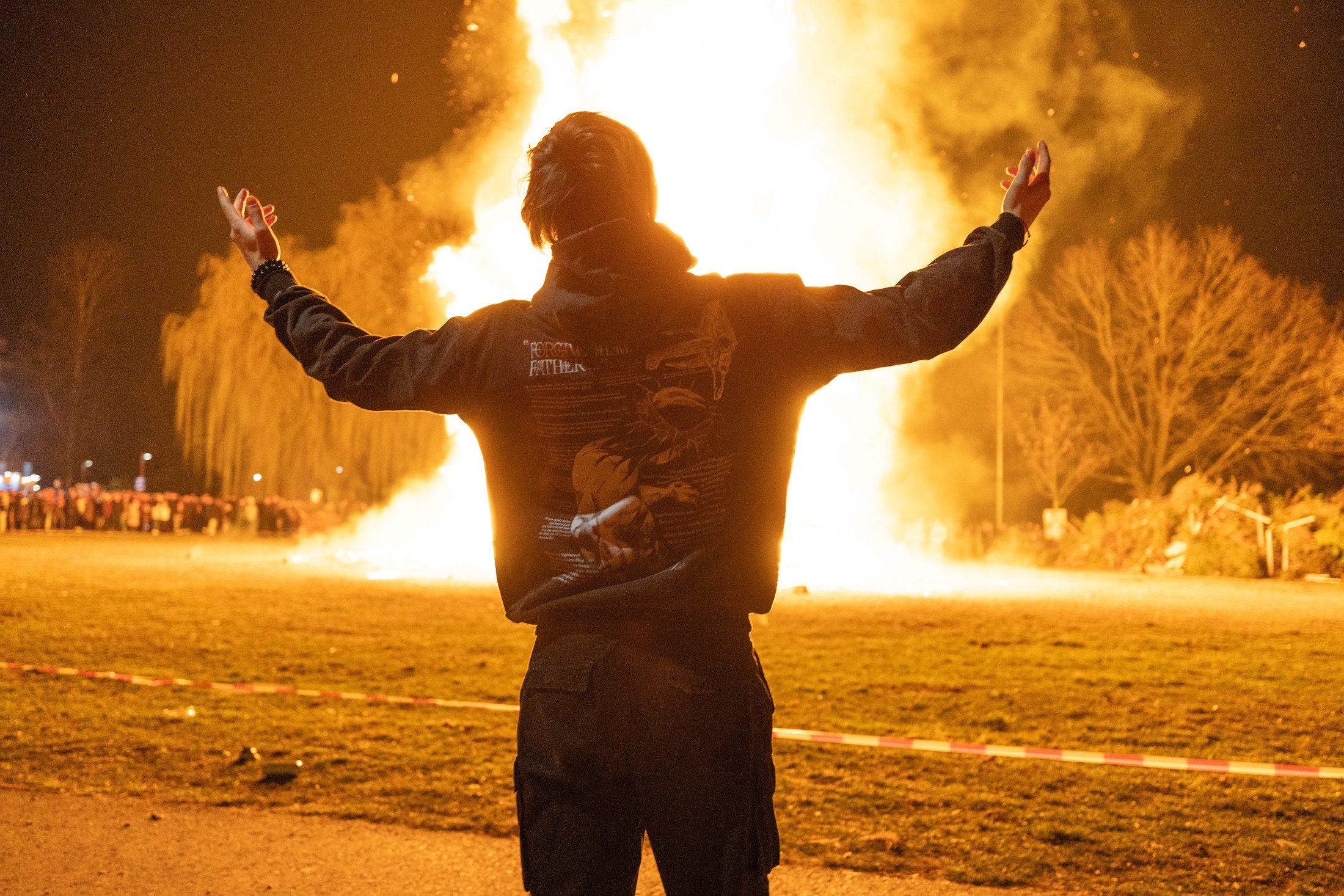 Person mit ausgebreiteten Armen vor einem großen Funkenfeuer